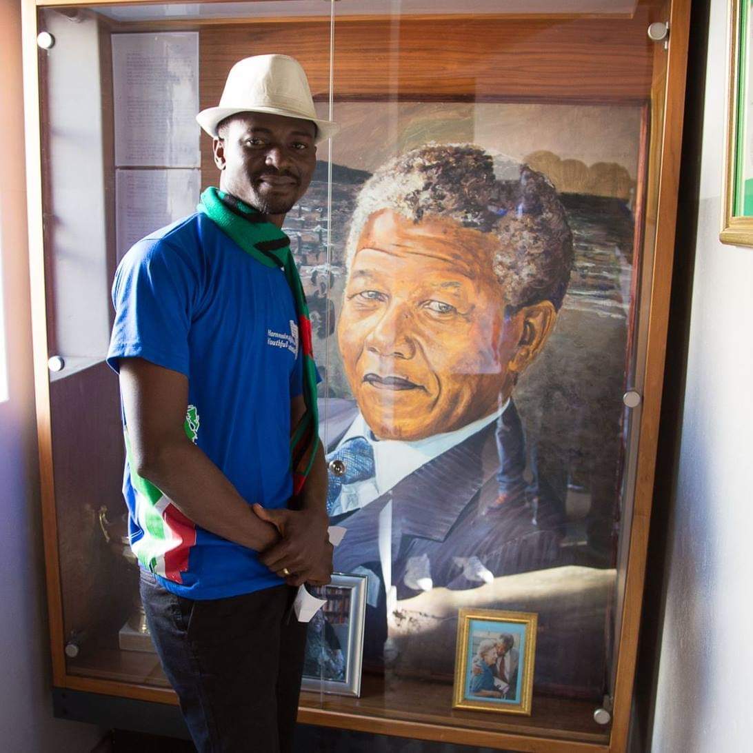 Nelson Madiba Amo visiting the home of Nelson Mandela, beside a painted portrait of Madiba